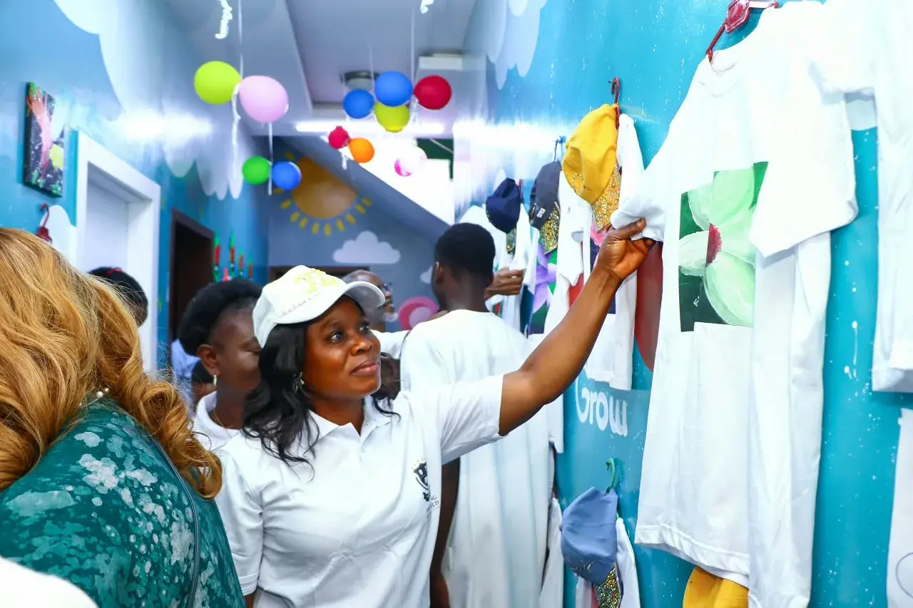 An adult showing artwork to children and families in a colourful classroom